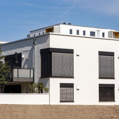 Residential property showcasing black roller shutters, ideal for explaining how do roller shutters work in terms of noise reduction and security.